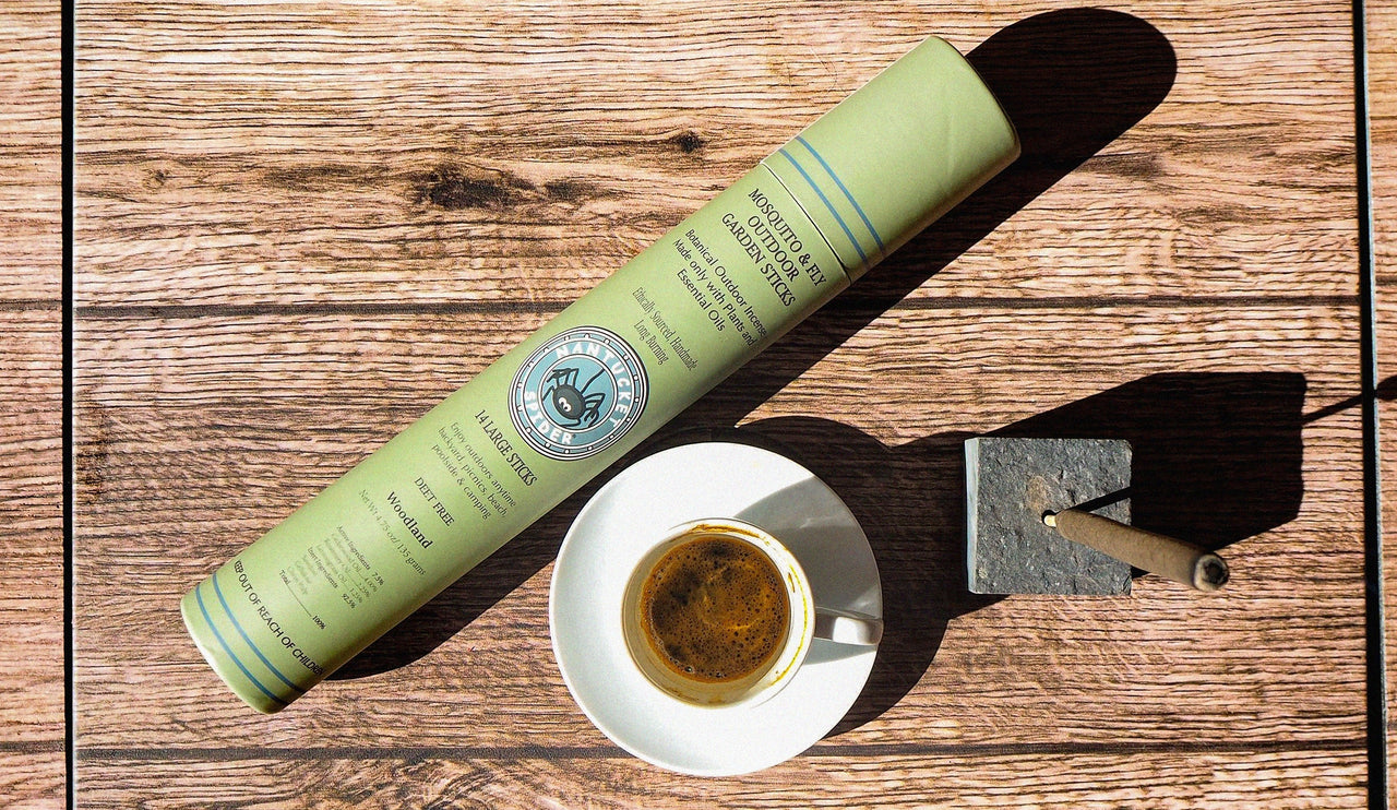 Green cylindrical container and white cup with saucer on a wooden surface